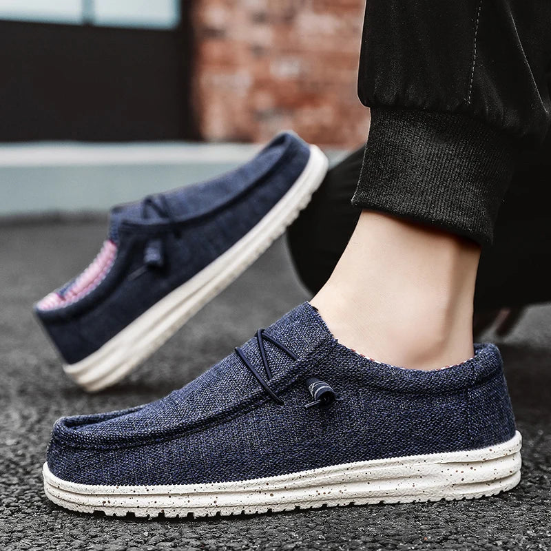 Navy blue loafers with white soles worn by a person on a dark surface.