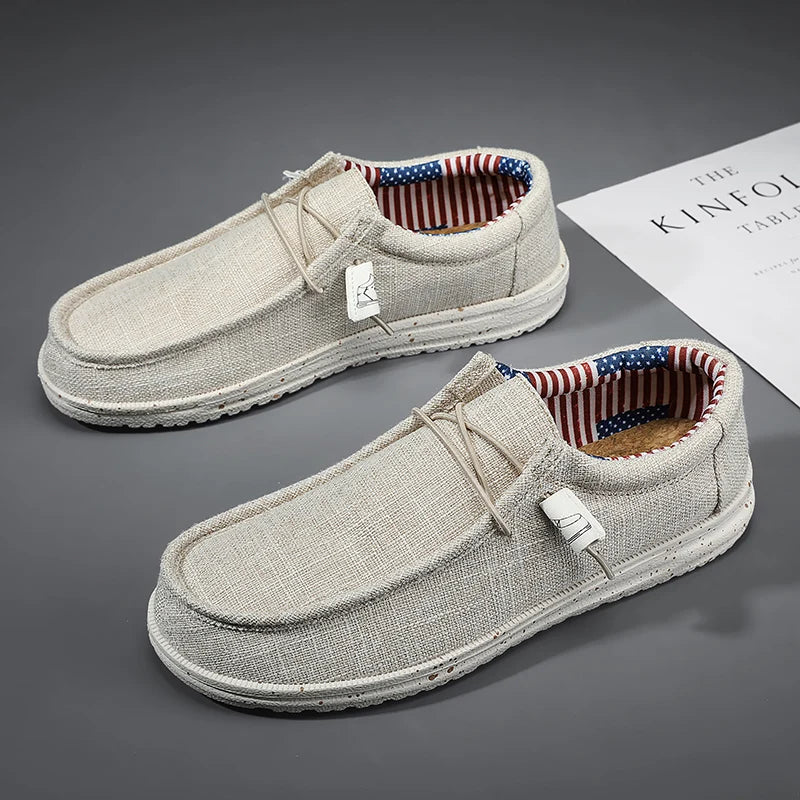 Pair of beige loafers with American flag lining on a gray surface.