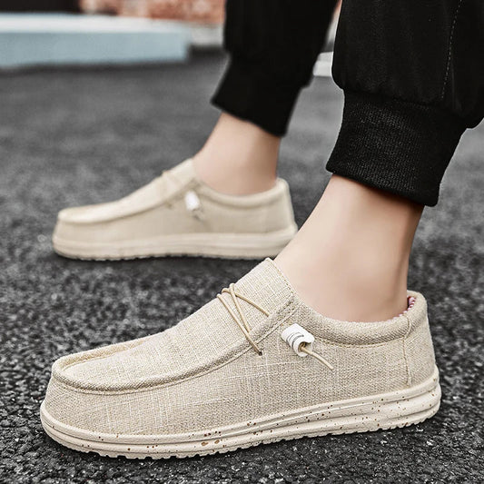 Beige slip-on shoes worn on a black asphalt surface