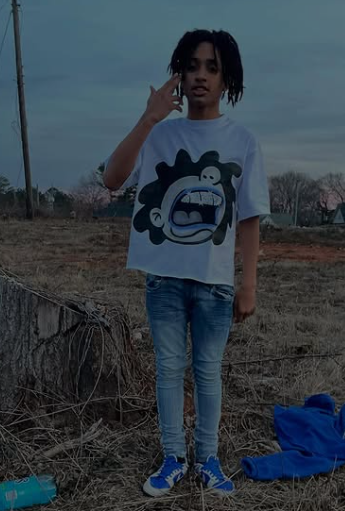 Person wearing a white t-shirt with a graphic design, standing outdoors in a field.