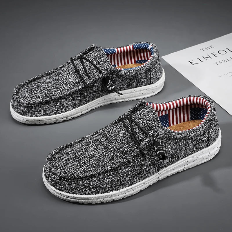 Pair of black loafers with American flag lining on a gray surface.