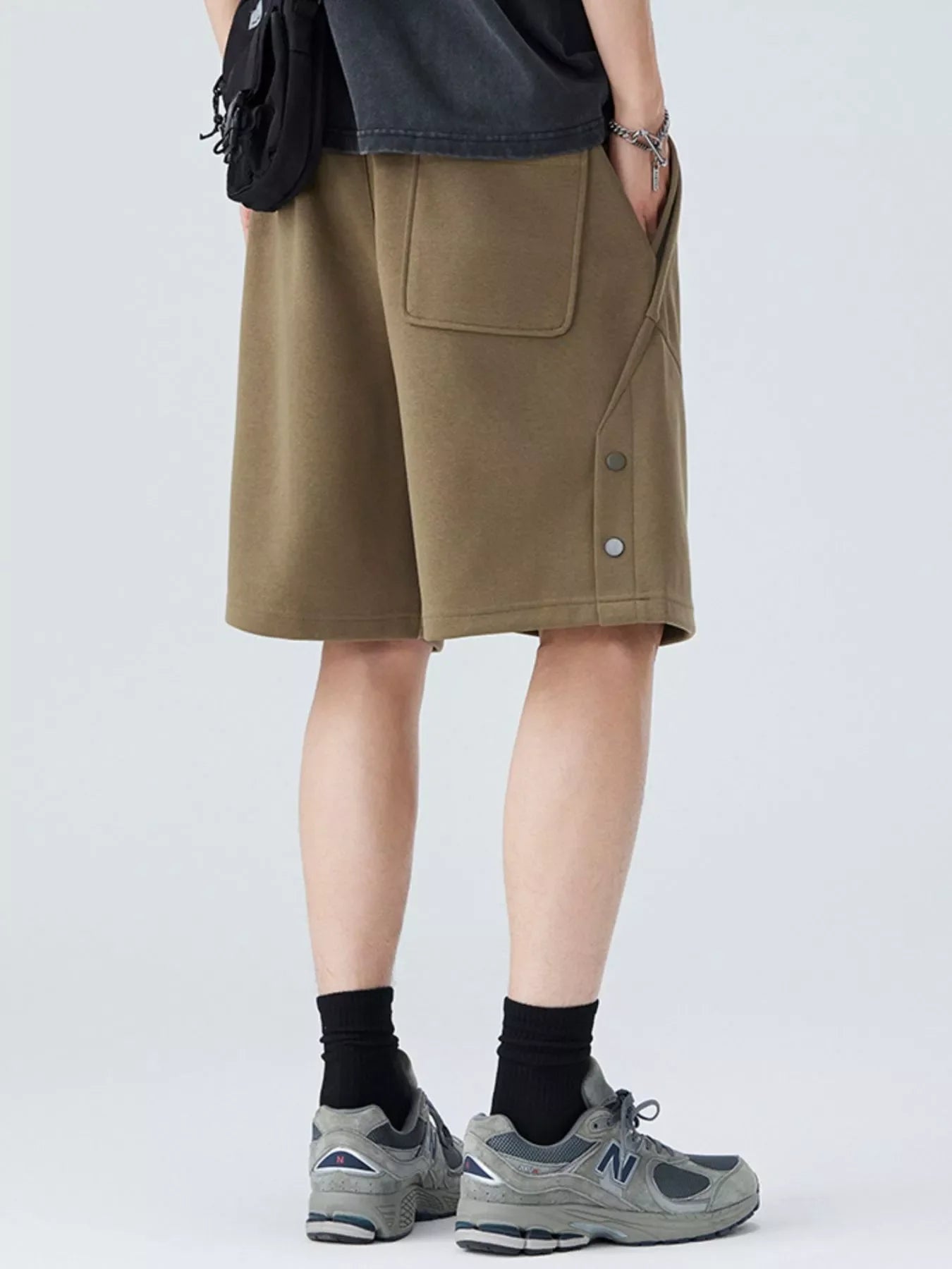 Person wearing khaki shorts with a plain background