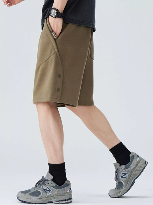 Person wearing khaki shorts with gray sneakers on a white background